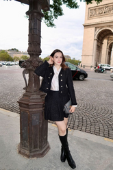 a lady in a white ruffle collared shirt, a black tweed jacket and a black tweed skirt